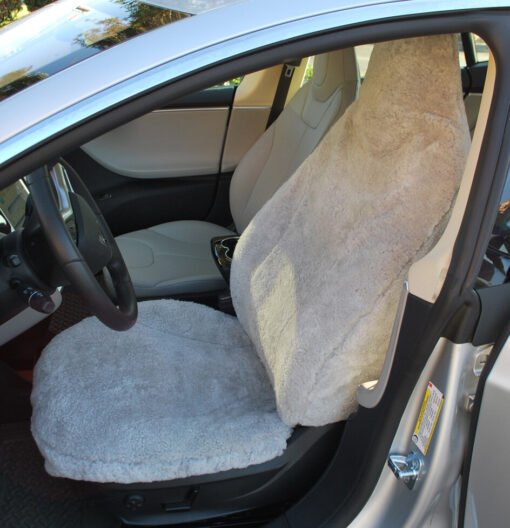 sheepskin seat cover installed in a Tesla Model S. The cover is a light gray color and appears to be made of real sheepskin.