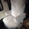 chair covered in a sheepskin seat cover. The seat cover is a light gray color and appears to be made of real sheepskin. The cover is fitted to the chair and covers the seat, back, and armrests.