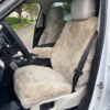 a sheepskin seat cover installed in a Range Rover. The cover is a light brown color and be made of real sheepskin