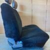 a black sheepskin seat cover for a car seat. It covers both the seat bottom and the backrest.