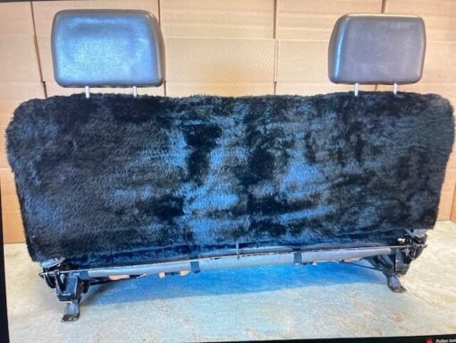 a black sheepskin seat cover for a truck, a bench seat cover, covering the entire back seat.