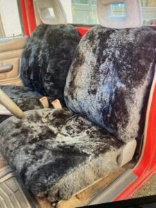 a pair of black sheepskin seat covers installed in a truck.