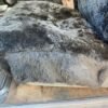 a black sheepskin seat cover for a car seat. It covers the bottom cushion of the seat.