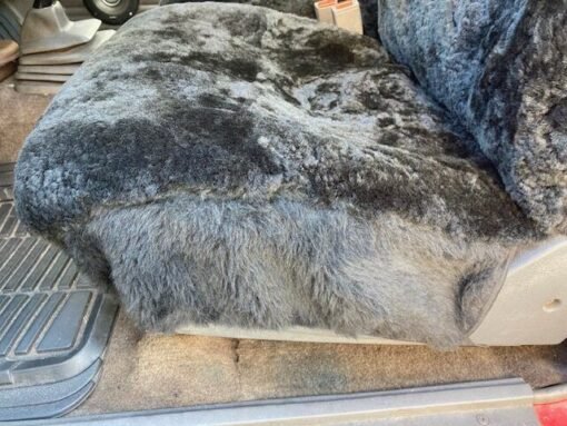 a black sheepskin seat cover for a car seat. It covers the bottom cushion of the seat.