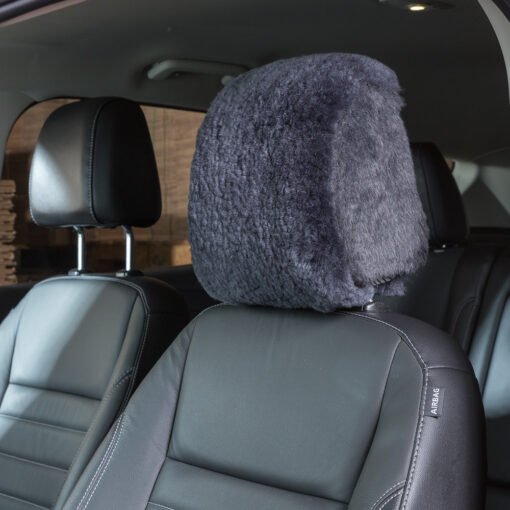 sheepskin headrest cover installed on a car seat. The cover is a dark gray color