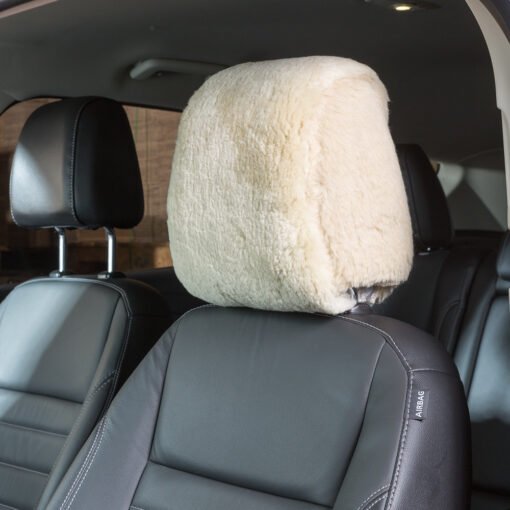 sheepskin headrest cover installed on a car seat. The cover is a light gray color